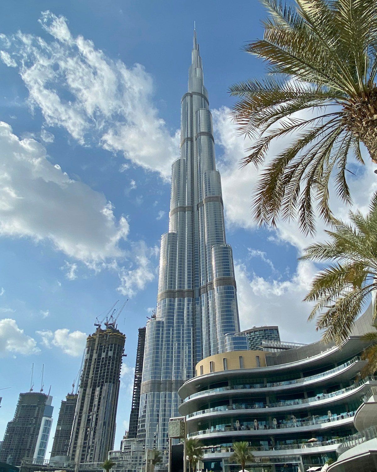 Home Burj Khalifa against a bright blue sky framed by palm trees – Dubai property for UK investors